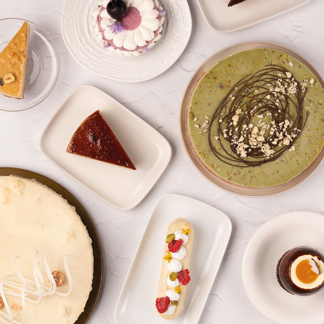 Vedere de sus cu deserturi asortate: cheesecake, flan, tartă cu fistic, eclair și pahare cu mousse de ciocolată