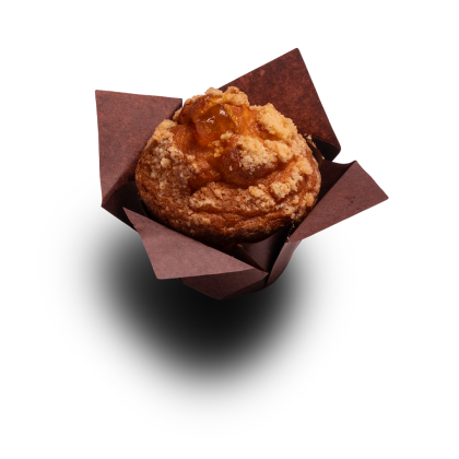 Brioșă aurie cu crumble streusel și umplutură de fructe, în formă de hârtie maro, pe fundal alb.