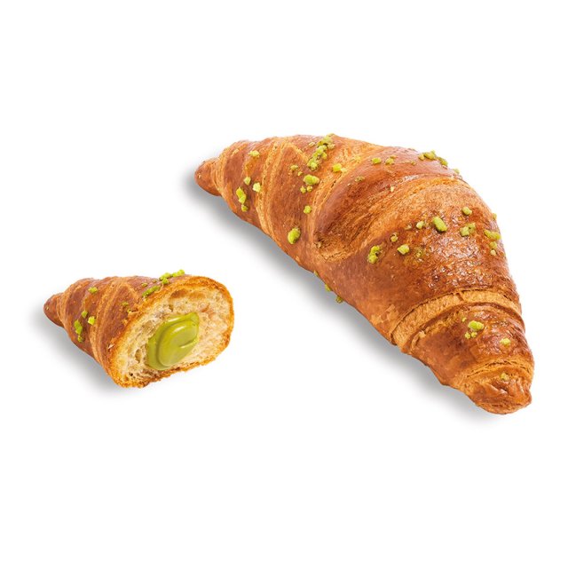 Croissant auriu cu fistic pisat, o jumătate arată o umplutură cremoasă verde de fistic.