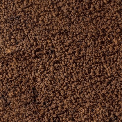 Prim-plan cu sol brun fărâmicios sau zaț de cafea, cu textură grosieră și granulată.