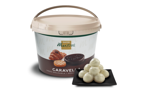 Găleată de cremă tartinabilă Master Martini Caravella cu trufe de ciocolată albă pe o farfurie pătrată neagră.